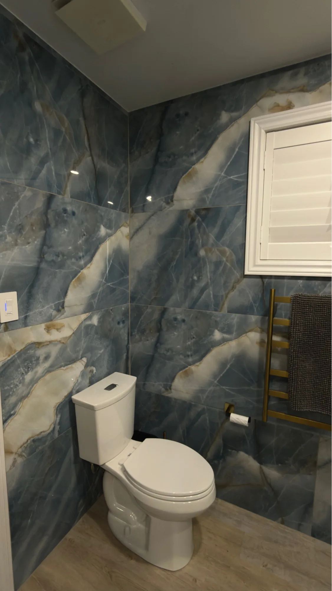 Blue onyx tile bathroom with gold towel warmer and plantation shutters — D&D Interior Services