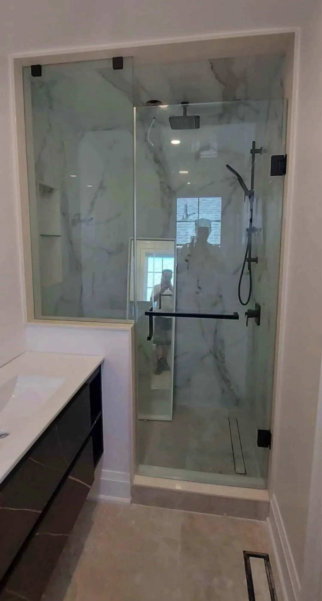 Carrara marble walk-in shower with frameless glass enclosure and black fixtures — D&D Interior Services Kitchener-Waterloo