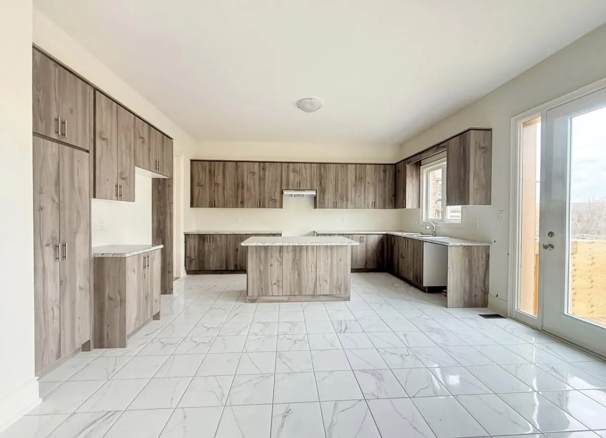 Wood-grain kitchen cabinetry and a central island above pale veined floor tiles